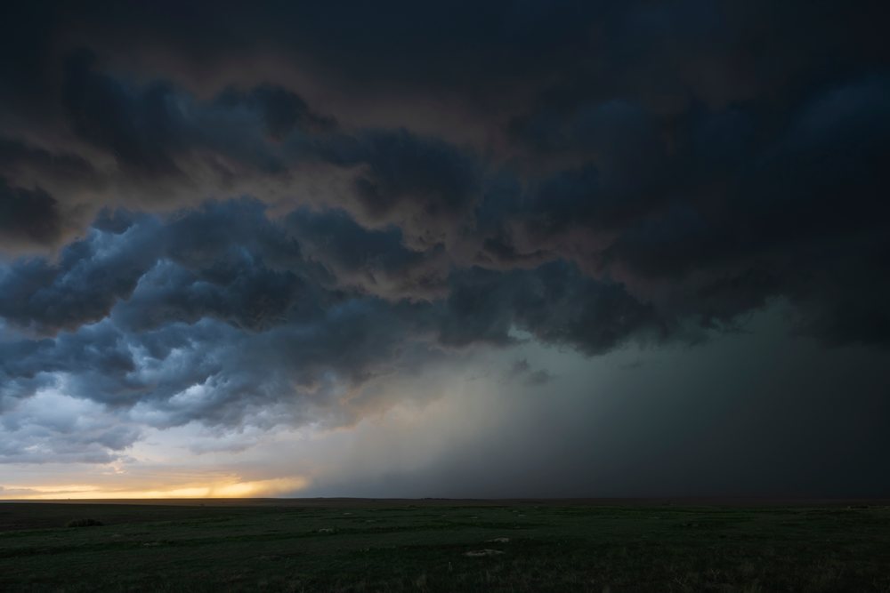Supercell storm clouds form over an open grassy field at Sunset in Tornado Alley, Storm Chasing, Weather, Environmental Issues, Seibert, Colorado, USA.