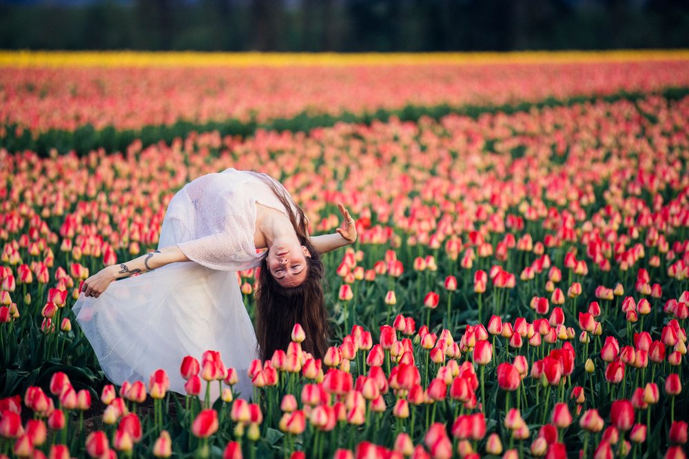Woman dancing gracefully in a vibrant red tulip field outdoors during spring, USA.