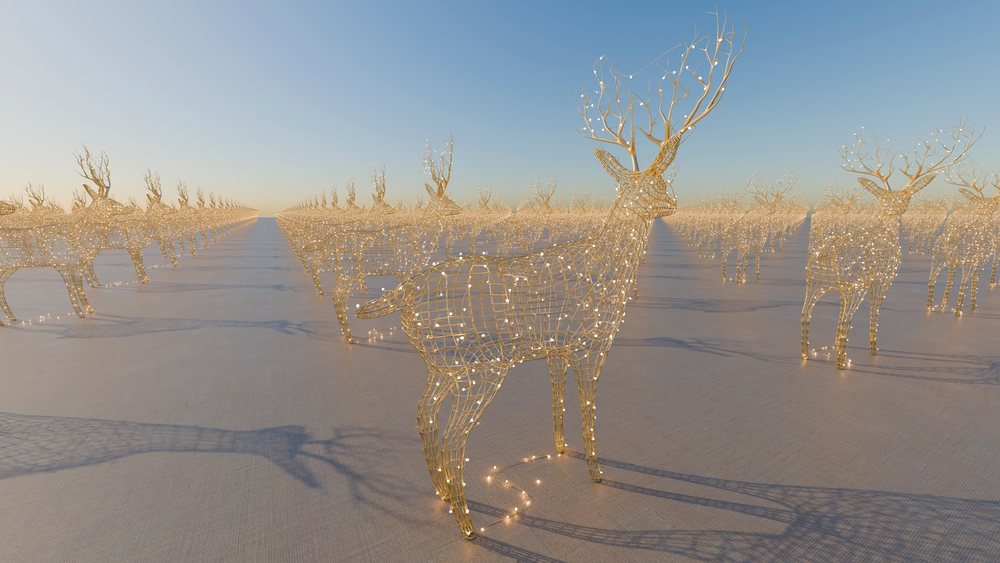 Wireframe deer sculptures decorated with small glowing lights arranged in rows on an open ground under a clear evening sky.
