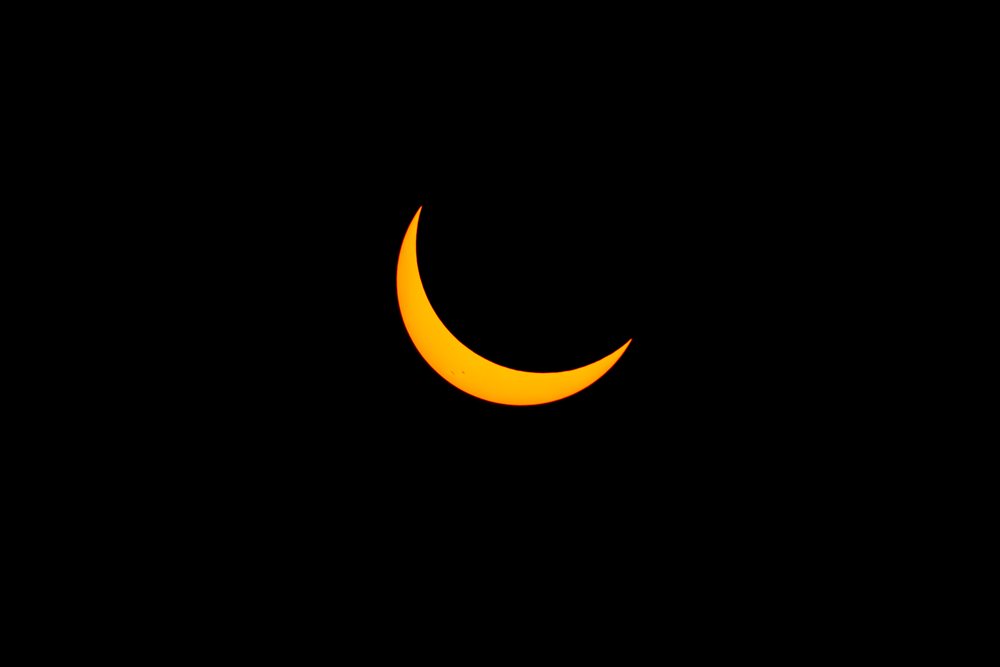 Solar eclipse creates a crescent sun visible over the dark sky of, Los Angeles, USA.