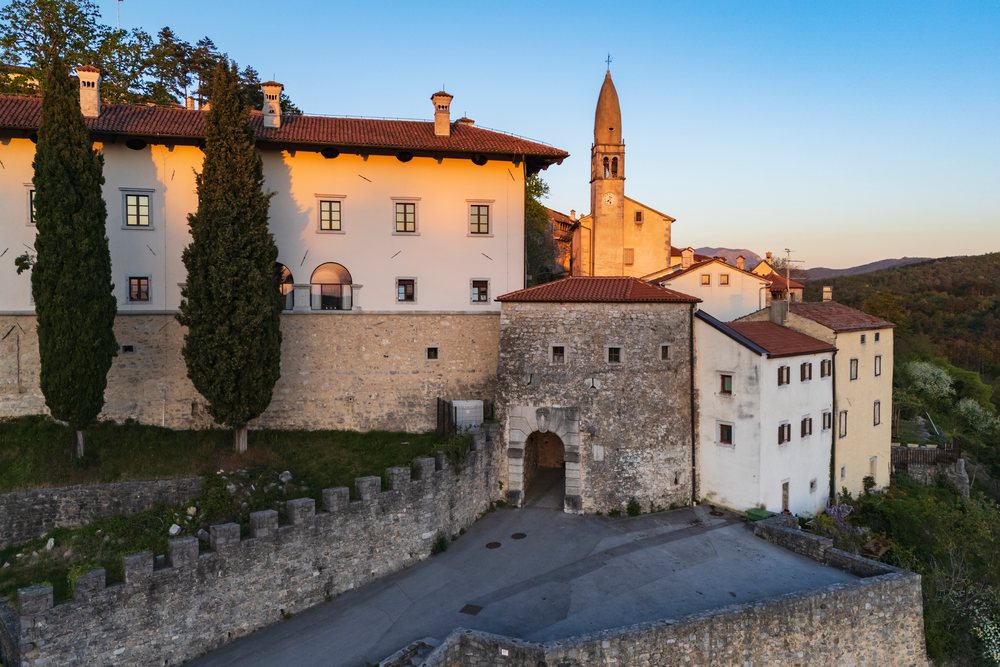 Stone city gate with arched entrance and Church of St Daniel, landscape, cityscape, Štanjel, Slovenia.