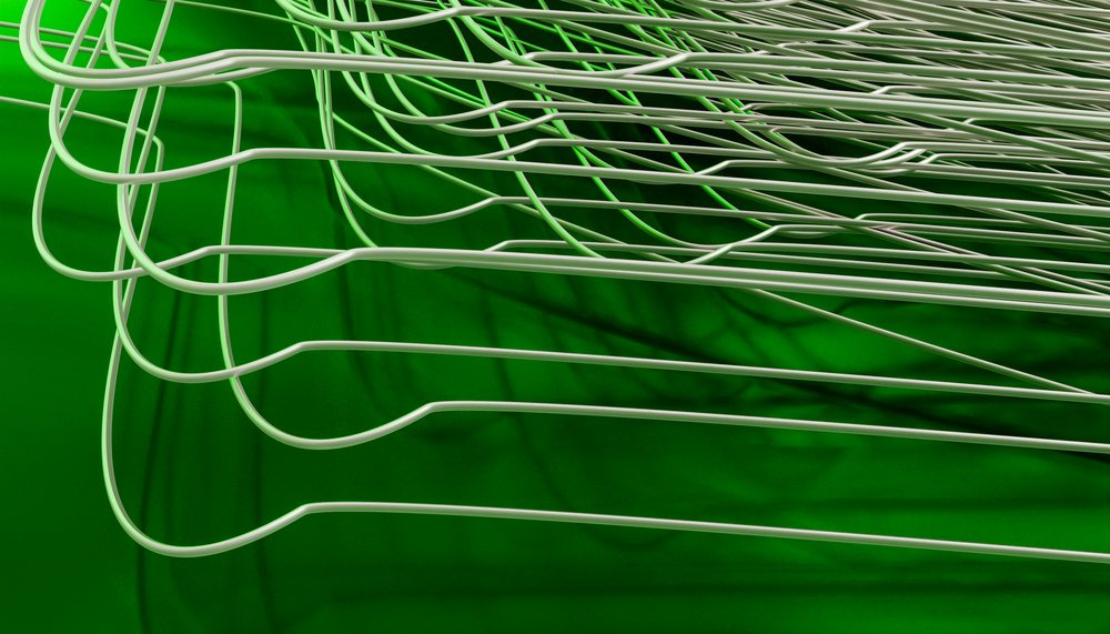 Curved white wires overlap and cast shadows on a bright green surface, forming an abstract network pattern.