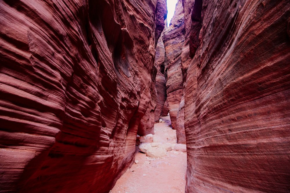 Narrow sandstone slot canyon with rocky path and red rock erosion patterns in Buckskin Gulch, Utah, USA.