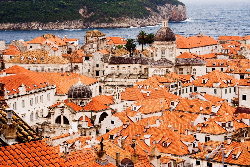Historic red tile rooftops and church domes overlook the Mediterranean Sea coastline, Croatia.