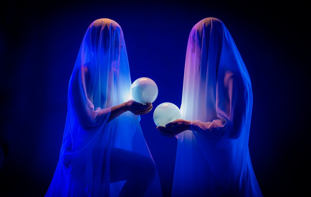 Two ethereal figures draped in translucent veils hold glowing crystal balls, ghosts, USA.