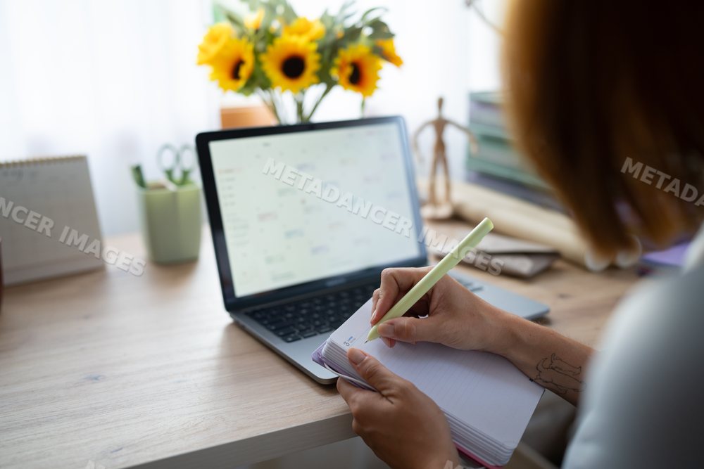 A white woman writes notes while working remotely at home in Spain