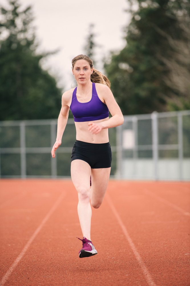 Woman running on an outdoor track during athletic training, USA.