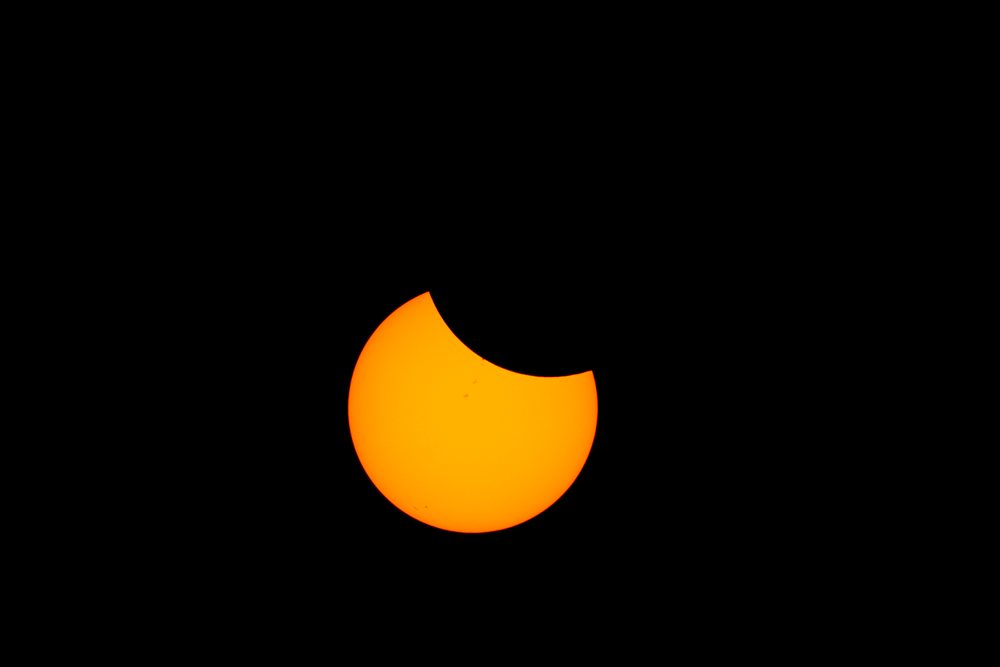 Partial solar eclipse with visible sunspots occurring over Los Angeles under a black night sky, USA.