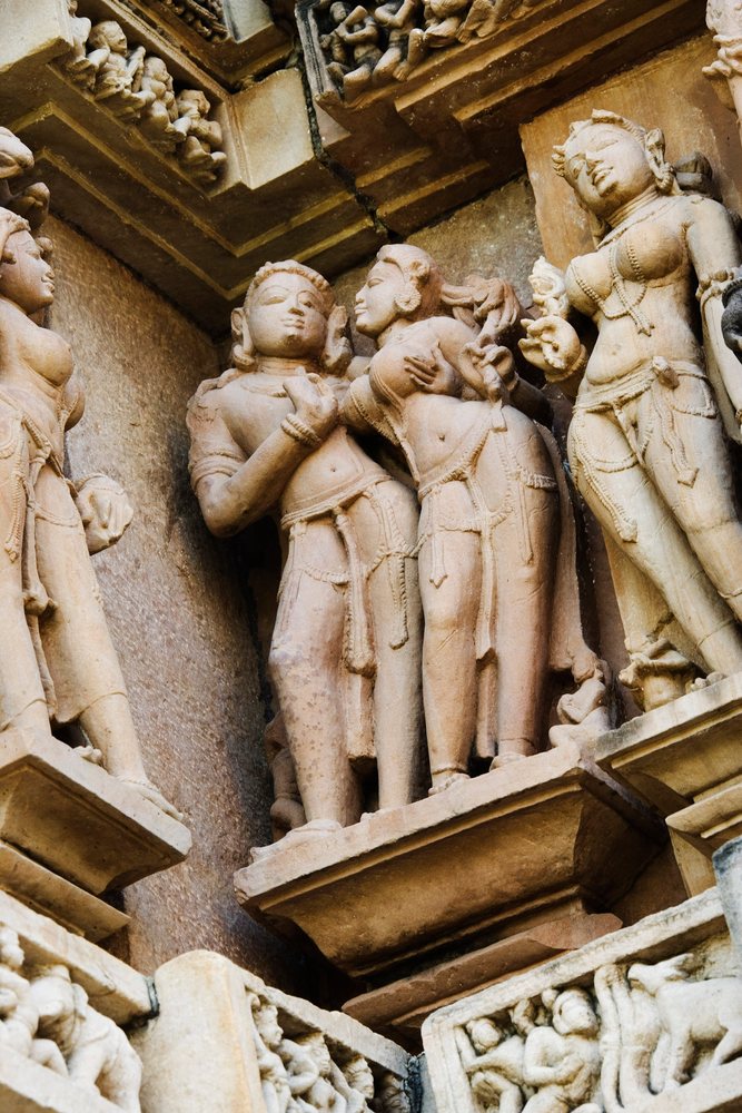 Stone sculptures carved into Khajuraho temple walls depicting intimate scenes, Madhya Pradesh, India.
