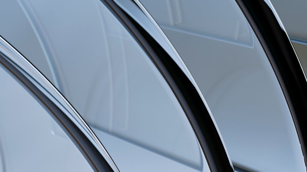 Close-up of curved chrome metal surfaces reflecting light with a modern abstract pattern.