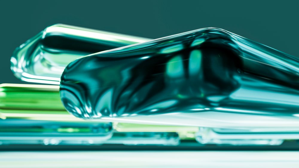 Stacked translucent blue and green glass blocks with abstract shapes and reflections in a modern artistic arrangement.