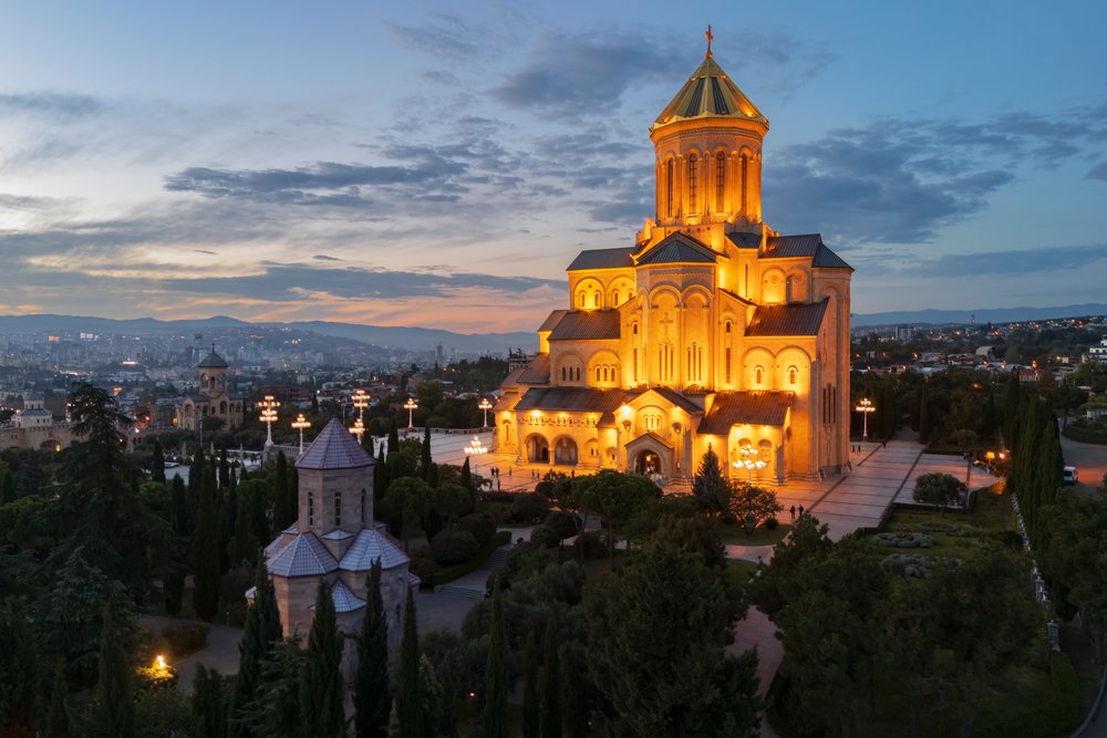 The Holy Trinity Cathedral of Tbilisi illuminated at Dusk with a cloudy sky and cityscape, Skylines, Georgia.