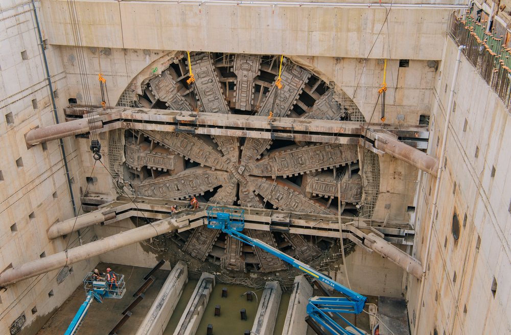 A large tunnel boring machine is set in a deep excavation shaft with workers and machinery at a construction site, the tunnel boring machine, drilling, USA.