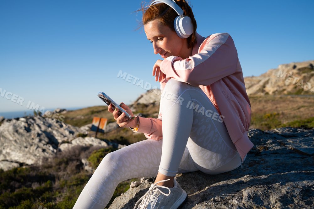 White Woman wearing headphones using smartphone