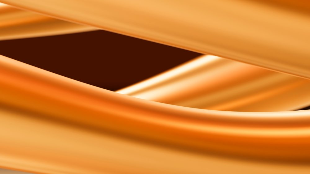 Close-up of flowing orange fabric with smooth texture and soft folds creating an abstract pattern.