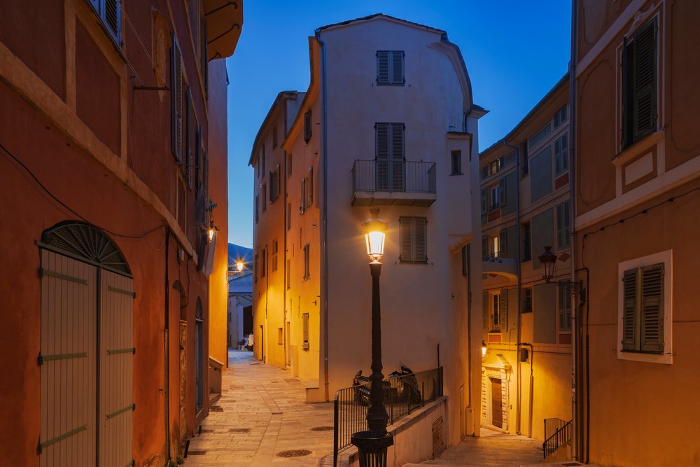Narrow cobblestone street in Bastia's Old Citadel at Dusk with illuminated street lamp and historic Mediterranean buildings, Travel Photography, Corsica, France.