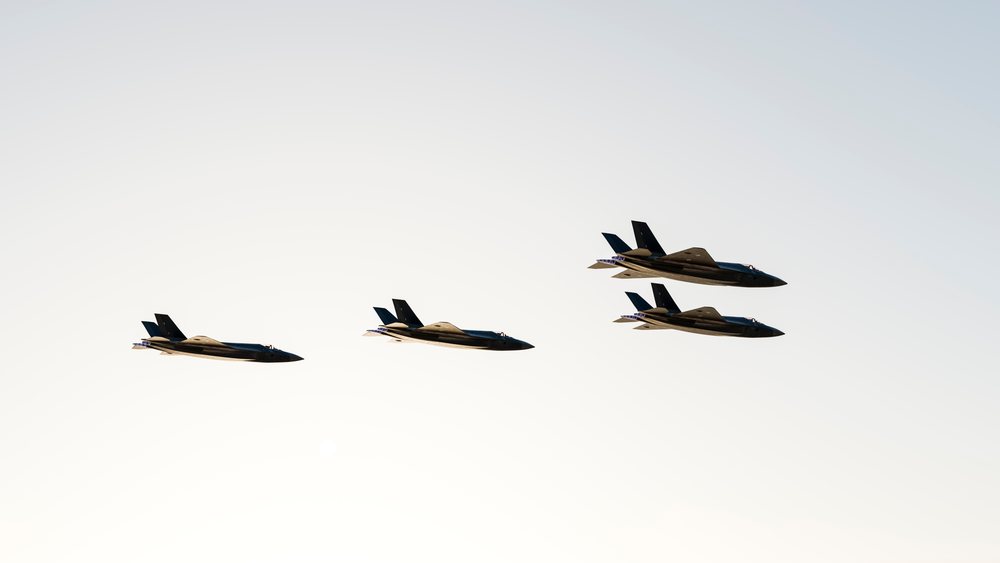 Four fighter jets fly in close formation against a clear sky, defense, war, security, military.