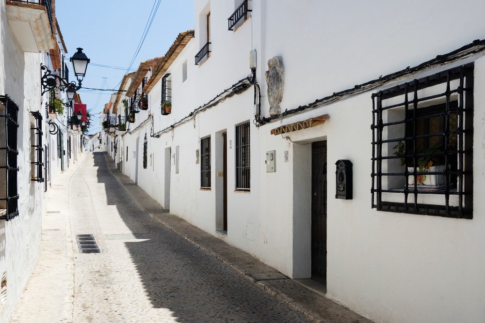 Narrow cobblestone street lined with white houses, Valencia, Spain.