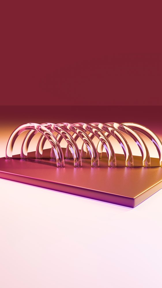 Close-up of shiny spiral metal rings with reflective surfaces under purple and pink lighting on a smooth flat background.