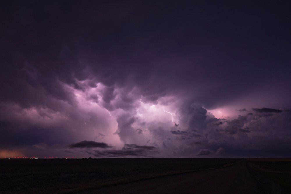 Lightning flashes behind turbulent Storm clouds over a rural landscape in Tornado Alley, Storm Chasing, Weather, Environmental Issues, Burlington, Colorado, USA.