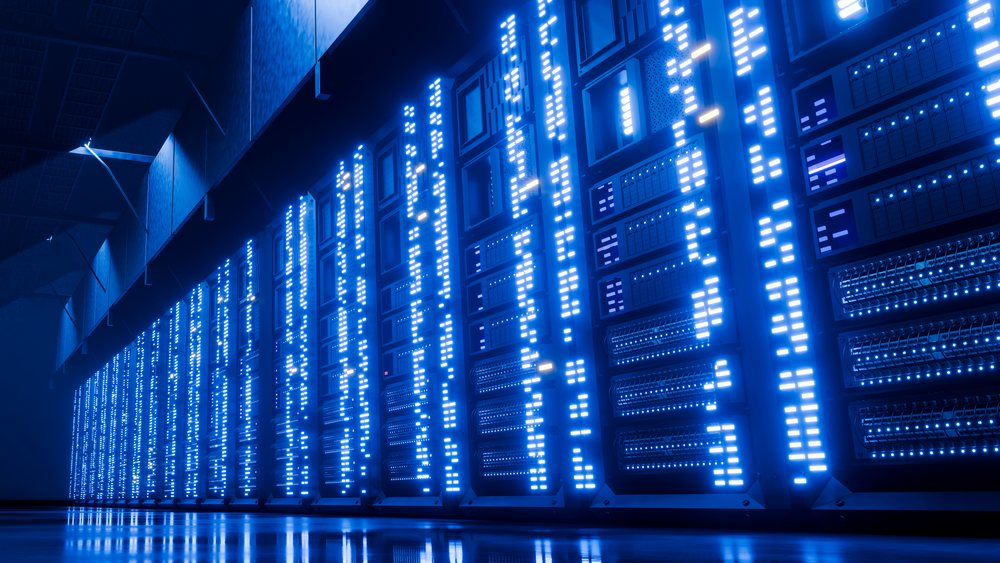 Rows of server racks with blue LED lights arranged in an indoor data center environment.