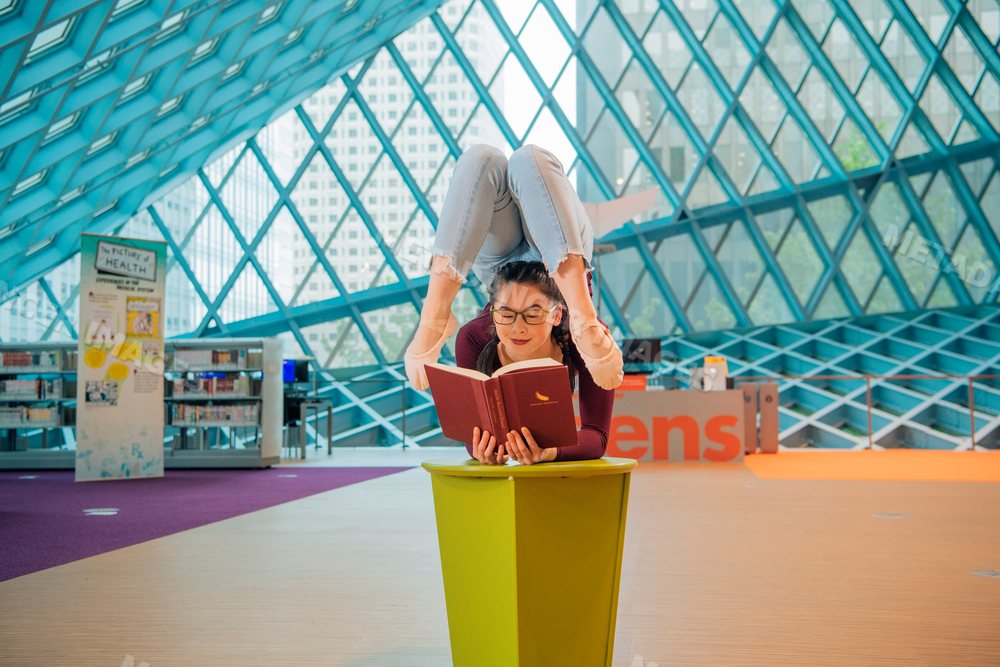 A woman contortionist reads a book inside the Seattle public library