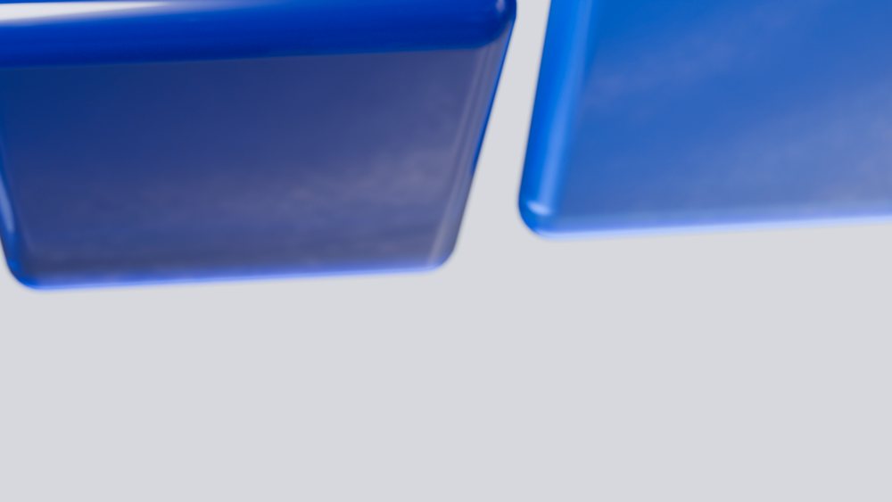 Blue geometric cubes with smooth texture arranged on a light surface in a minimalist abstract composition.