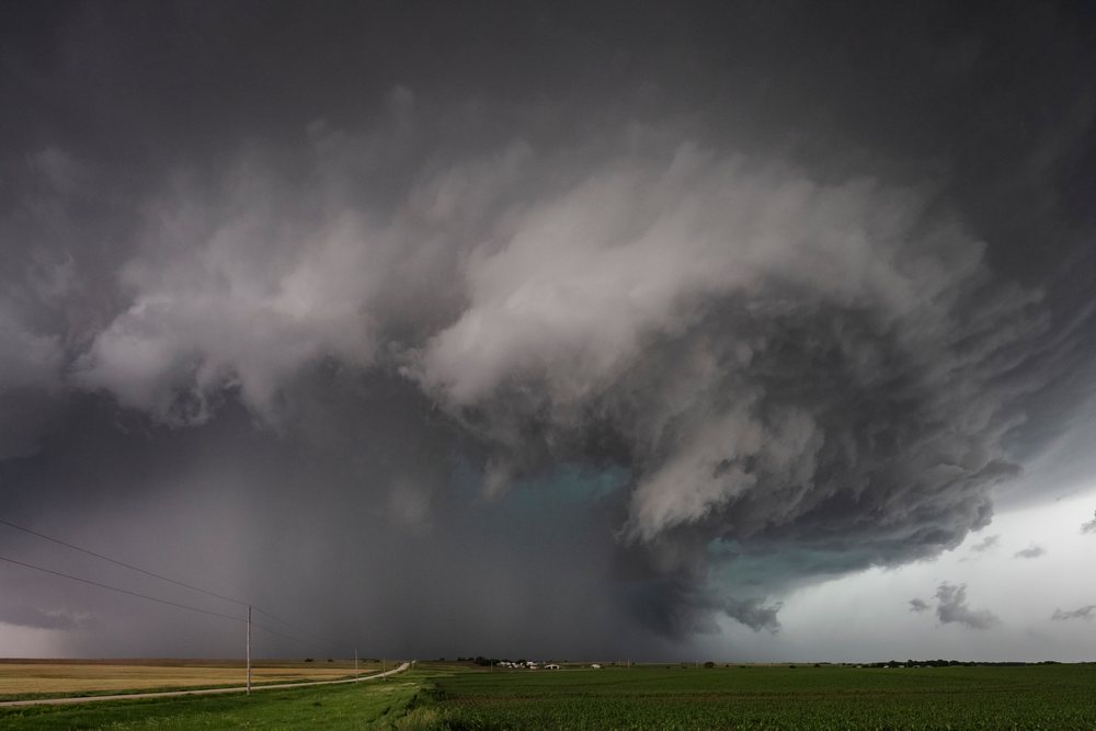 Large supercell storm with dark swirling clouds forms over green agricultural fields, Storm Chasing, Weather, Environmental Issues, Enterprise, Kansas, USA.