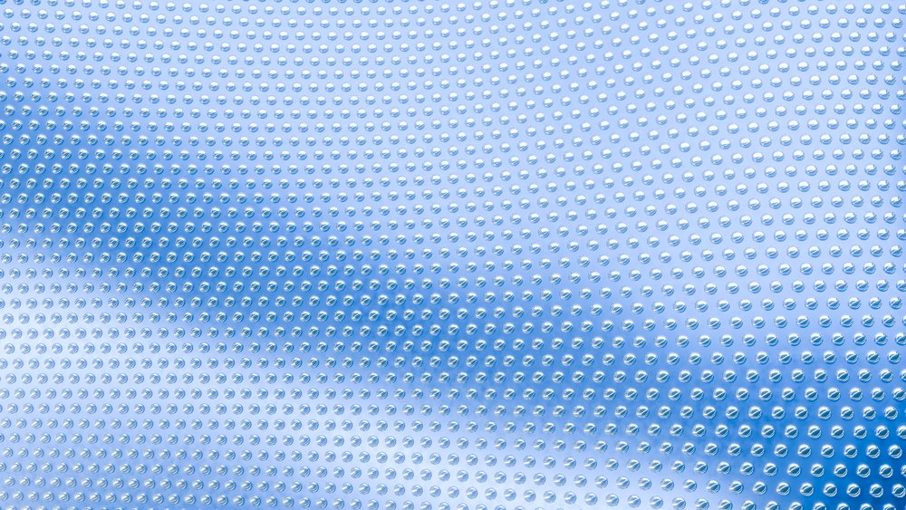 Transparent bubble wrap with circular air pockets used for protective packaging against a blue background.