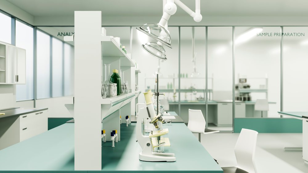 Microscope on laboratory bench with scientific glassware including bottles and test tubes in a clean sample preparation room.