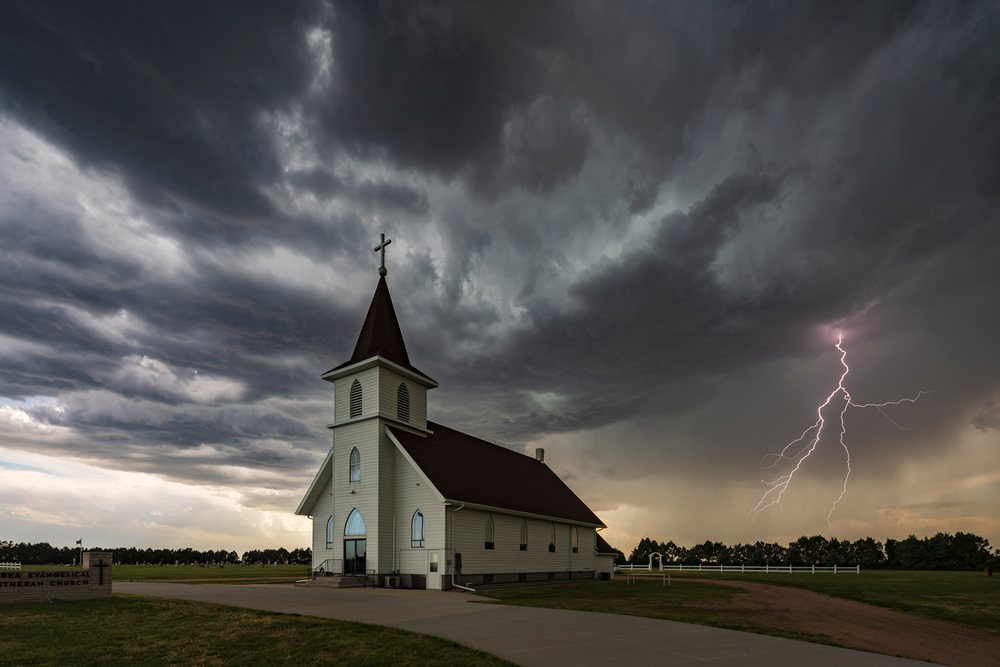 Lightning strikes near Berea Lutheran Church under dark storm clouds in rural, Chappell, Nebraska, USA.