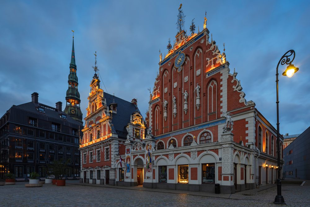 The House of the Black Heads historic building with illuminated façade and astronomical clock at dusk, cityscape, Riga, Latvia, Baltic States.