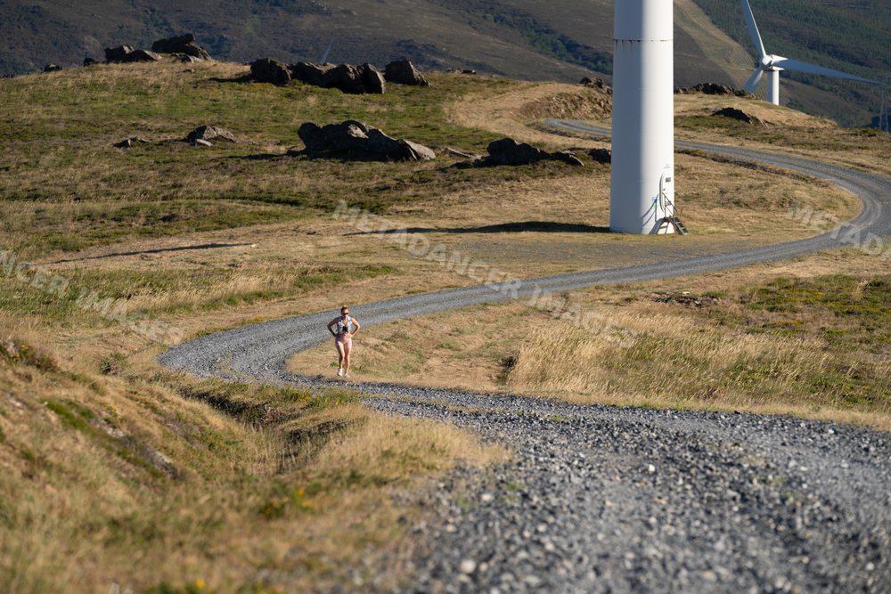 A white woman running on a gravel road