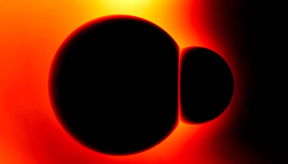 A solar eclipse showing the moon silhouetted against the sun with a bright solar corona glowing around it.