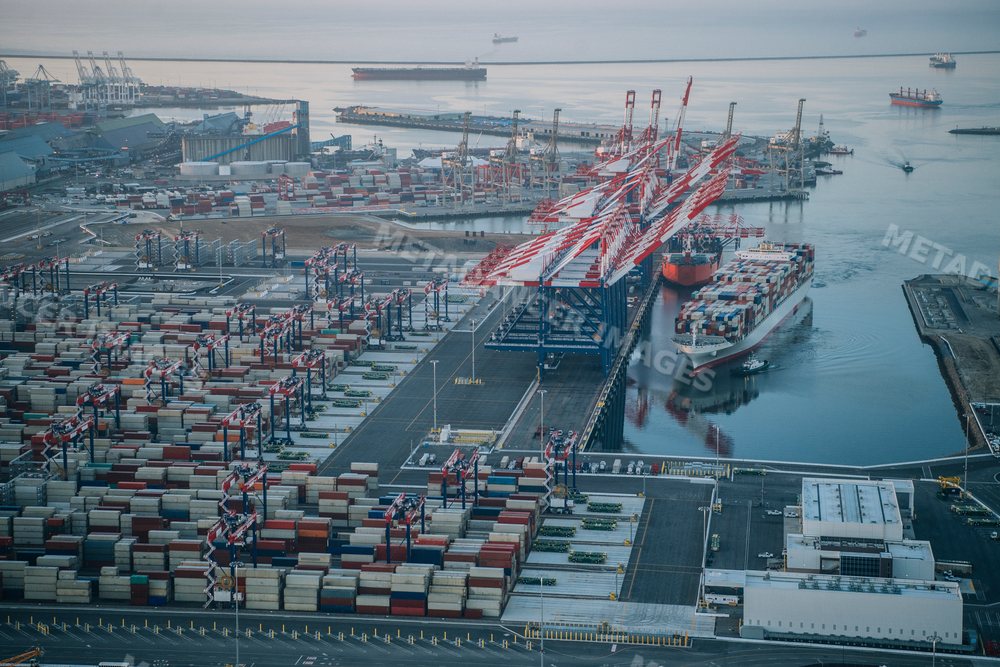 A container ship docked at a busy port with cranes and cargo