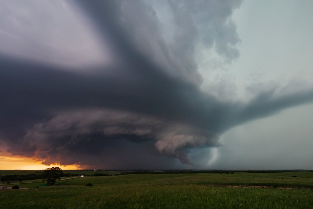 Tornado-warned supercell storm forms near Salinas, with dark clouds over open grassland at sunset, Storm Chasing, Weather, Environmental Issues, Herrington, Kansas, USA.