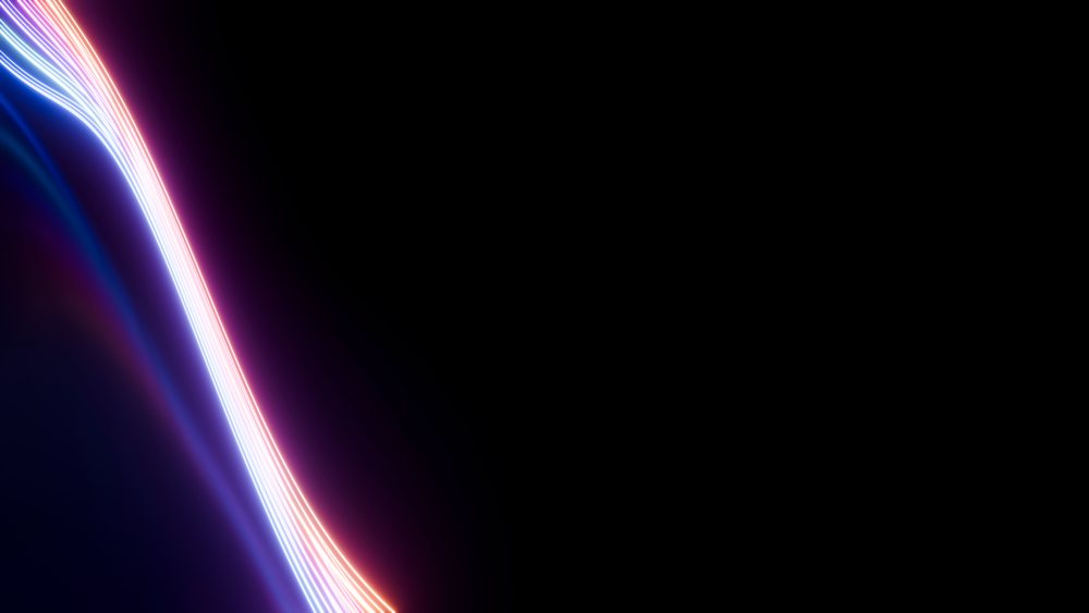 Curved multicolored neon light streaks in blue and pink glow on a dark background forming a wave shape.