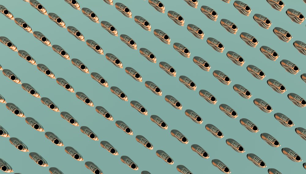 Shoes arranged in diagonal rows on a light teal background creating a repetitive pattern in a studio setup.