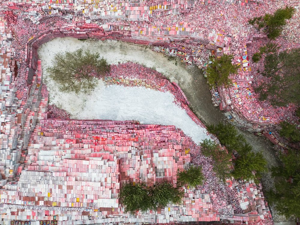 Aerial view of Jiana Mani city showing colorful stacked stones, winding pathways, and scattered green trees in an open outdoor landscape of Kham Tibet, China, Xinzhaia, Qinghai Province, People's Republic of China.