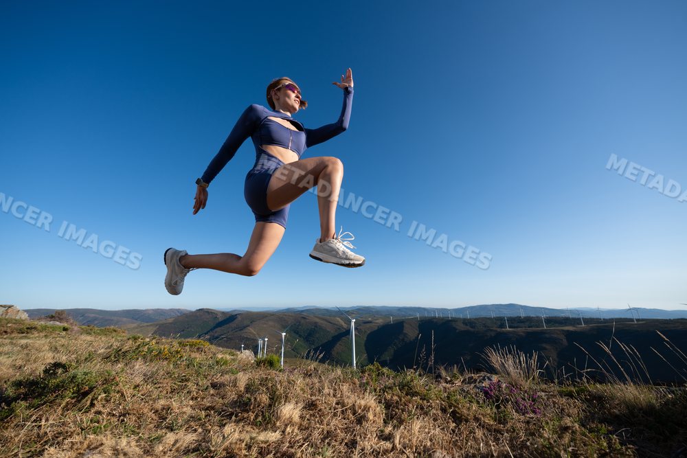 White Woman in athletic wear jumping outdoors in the hills of Galicia