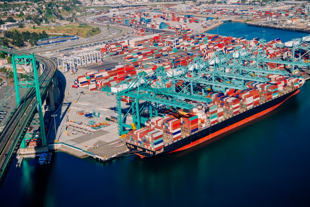 Container ship loaded with cargo containers at a busy shipping terminal with container cranes at the, Port of Long Beach, CA, USA.