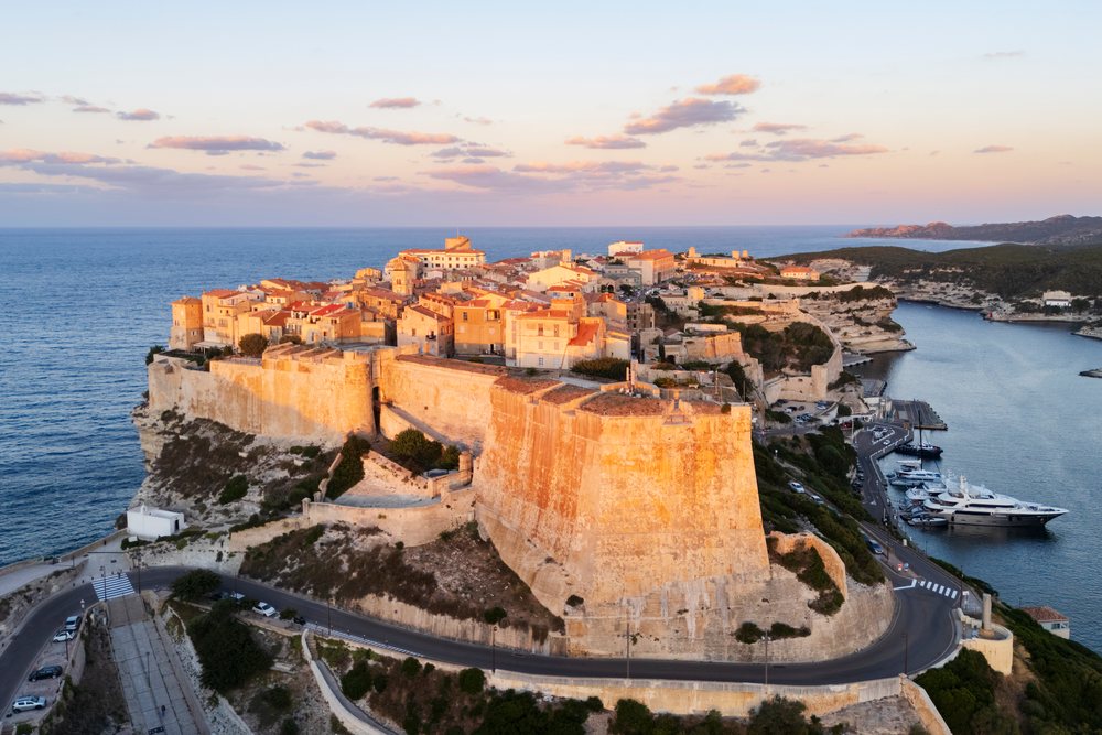 Sunrise over the Citadel and historic stone buildings on the cliff, overlooking the Mediterranean marina and coastline, Travel Photography, Bonifacio, Corsica, France.