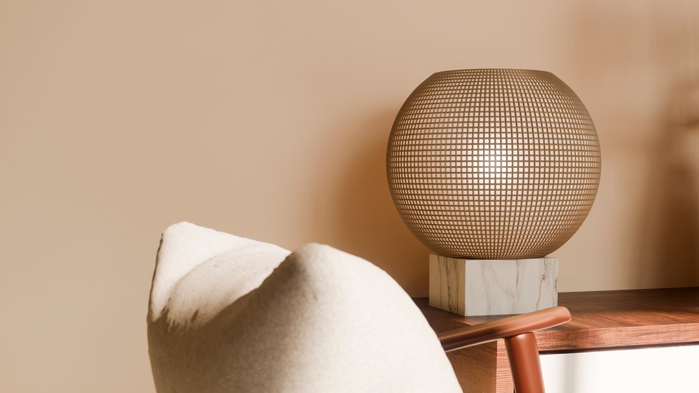 Modern decorative lamp with a round woven shade on a marble base standing on a wooden table against a beige wall in a modern interior.