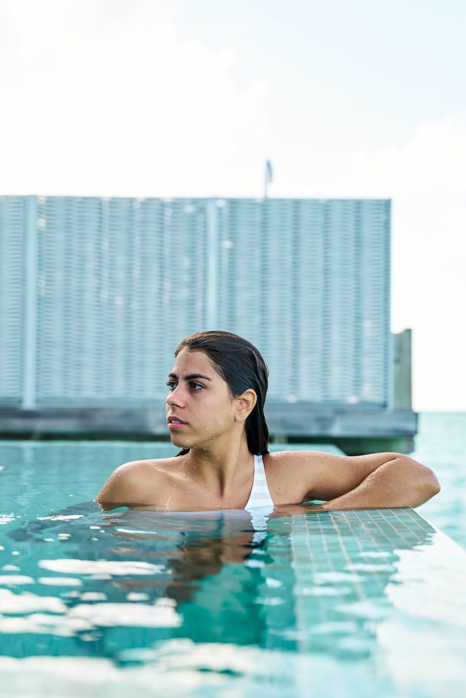 A white woman relaxes by the edge of a swimming pool