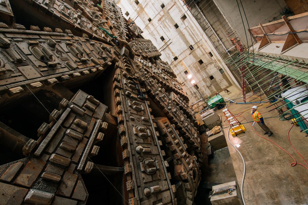 Two construction workers inspect a tunnel boring machine inside an industrial underground construction site, Bertha, drilling, USA.