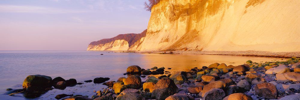Chalk cliffs along the rocky coast of Rugen Island at sunset with calm sea waters, Chalk Cliffs Rugen Island, Germany.