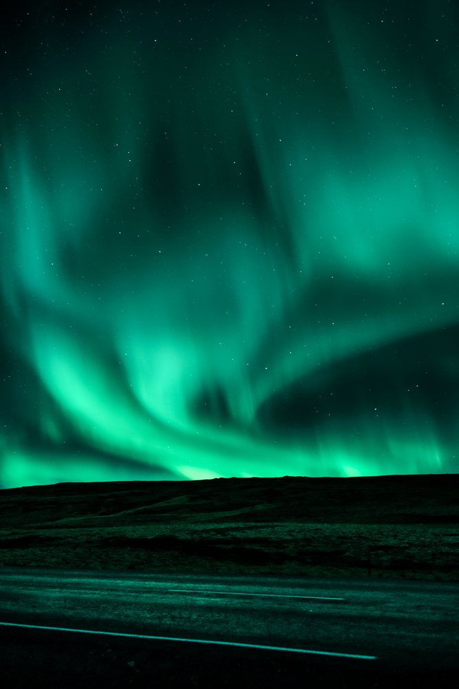 Green northern lights illuminate the night sky over Iceland landscape