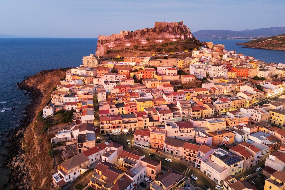 Castelsardo hilltop Citadel and Mediterranean coastal town with rocky coastline illuminated at Dusk, Travel Images, Sardinia, Italy.