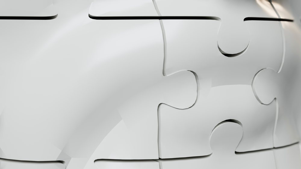 Close-up of interlocking white jigsaw puzzle pieces connected in a pattern.