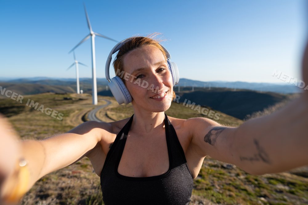 Young white woman taking a selfie at a wind farm in Galicia, Spain